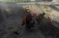 FILE - *Inmate firefighter David Clary, 41, with the Mount Gleason Conservation Camp 16, walks down a steep hill after eight hours of fighting a wildfire in the Angeles National Forest near Azusa, Calif., Saturday, Sept. 5, 2009. California currently has about 1,250 prisoners trained to fight fires and has used them since the 1940s. It pays its "Angels in Orange" $2.90 to $5.12 a day, plus an extra $1 an hour when they work during emergencies. (AP Photo/Jae C. Hong, File)