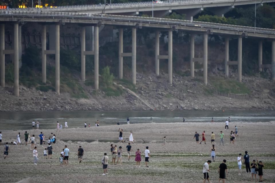 People walk along the dry riverbed of the Jialing River, a tributary of the Yangtze, in southwestern China's Chongqing Municipality, Saturday, Aug. 20, 2022. The very landscape of Chongqing, a megacity on the Yangtze River, has been transformed by China's worst heat wave since modern record-keeping began six decades ago, and an accompanying drought. (AP Photo/Mark Schiefelbein)