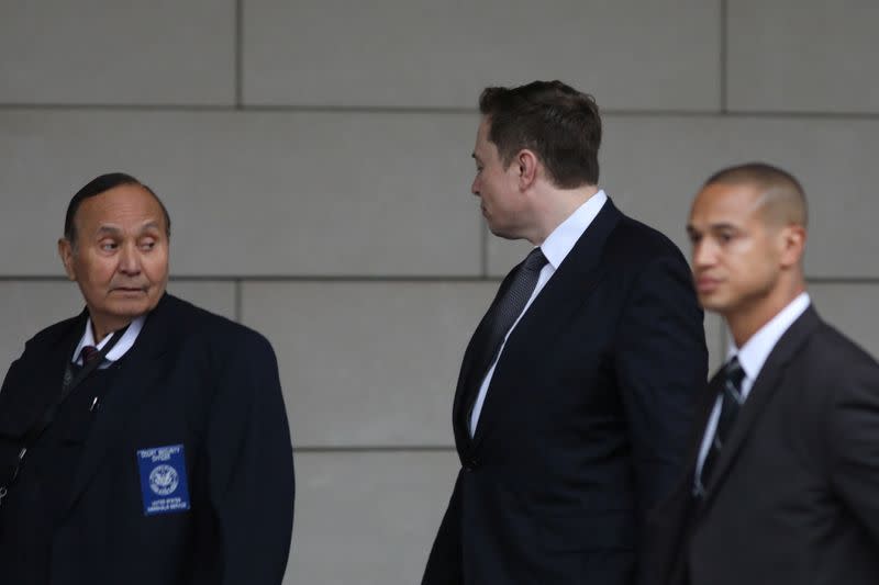 Elon Musk walks with his face turned away from cameras as he arrives at court for trial in Los Angeles