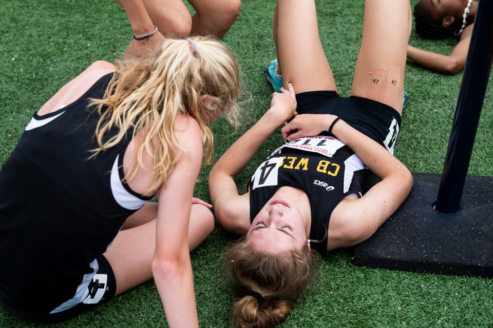 Members of CB West's 4x400-meter relay team, including anchor Mimi Duffy (right), rest on the turf after running their legs at the PIAA Track and Field Championships at Shippensburg University on Saturday, May 28, 2022.