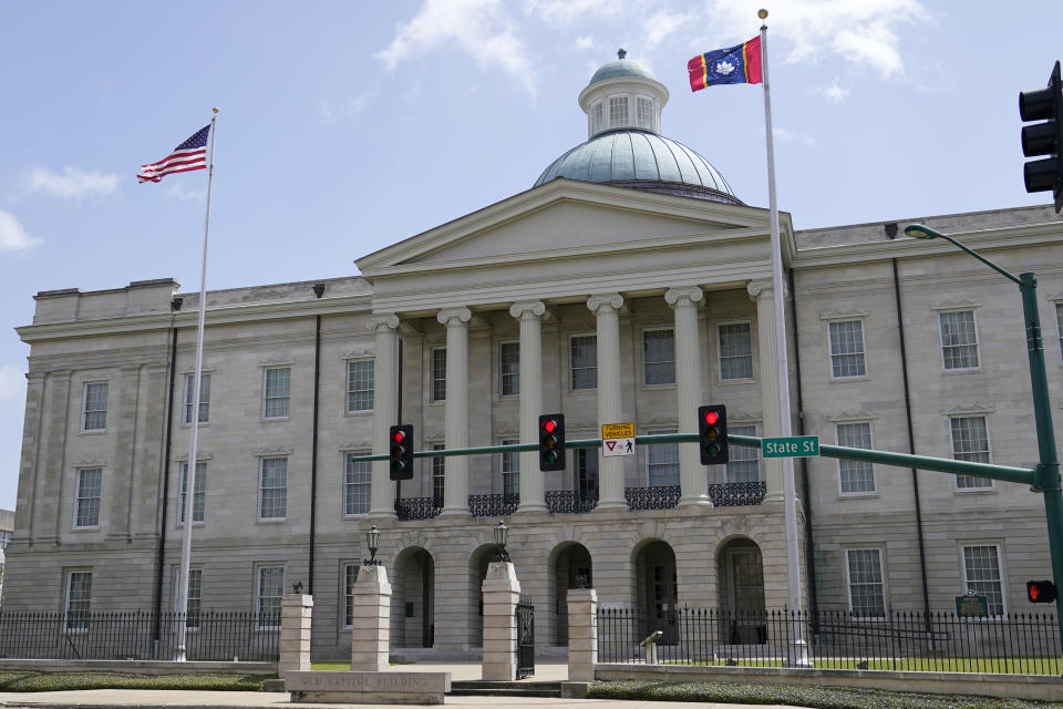 The magnolia flower centered banner chosen Wednesday, Sept. 2, 2020 by the Mississippi State Flag Commission flies adjacent to the American flag in a brisk wind, outside the Old State Capitol Museum in downtown Jackson, Miss. The nine member committee voted to recommend a design with the state flower, now known as the "In God We Trust," flag. That design will go on the November ballot for voters consideration and if approved, it will become the new state flag. (AP Photo/Rogelio V. Solis)