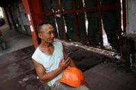 FILE PHOTO: A worker rests against a wall in an area filled with small blue-collar workshops in Kok Tsui in Hong Kong
