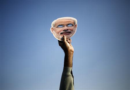 A supporter of India's main opposition Bharatiya Janata Party (BJP) holds up a mask of Hindu nationalist Narendra Modi, prime ministerial candidate for BJP and Gujarat's chief minister, during a rally ahead of the state elections in New Delhi in this November 30, 2013 file photo. REUTERS/Anindito Mukherjee/Files