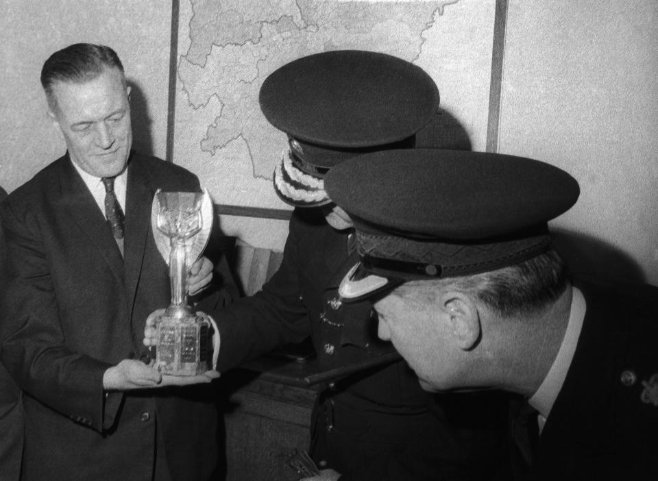 FILE - Detective Chief Inspector William Little, left, holds the World Cup, as Senior Commander John Lawlor, centre, and Chief Superintendent William Gilbert, admire the cup after its safe return to the police at Cannon Row Police Station, (Scotland Yard), London on March 28, 1966. The cup was returned to the police after it was found in the garden of David Corbett's home in Beulah Hill, Norwood, London, United Kingdom, by his mongrel dog "Pickles" who sniffed it out while being taken for a walk. (AP Photo/Rider-Rider, File)