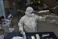 A health worker checks a rapid kit to test for COVID-19 in Hyderabad, India, Sunday, Dec. 13, 2020. (AP Photo/Mahesh Kumar A.)