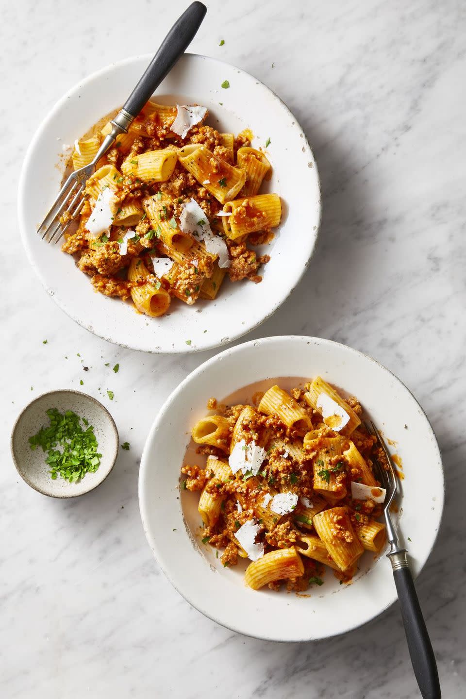 pork ragu rigatoni with shaved parmesan on a white bowl