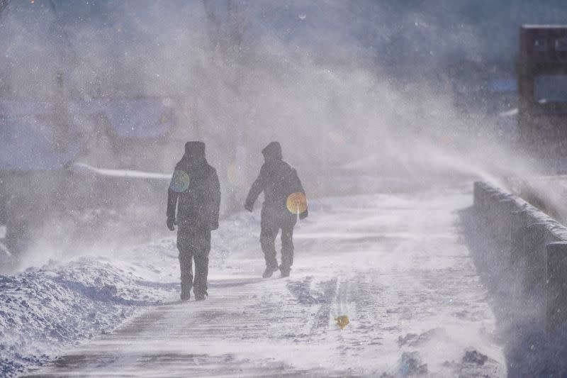 People walk across a snow-covered riverbank in Tongjiang