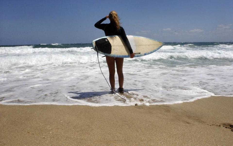 A surfer looks out over the ocean at Deerfield Beach for a set of waves in this file photo.