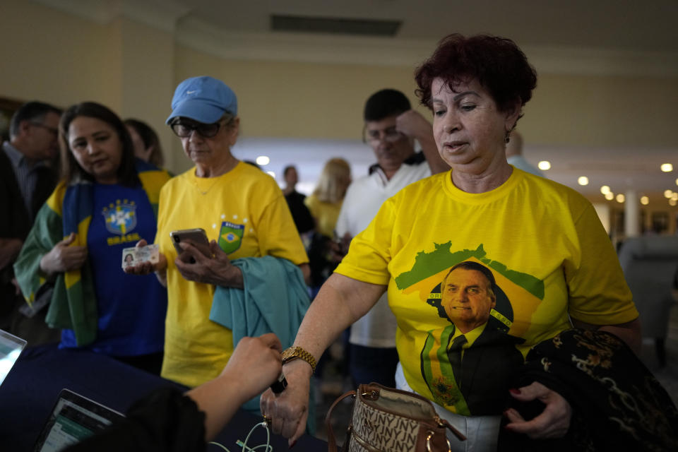 Maria Marquez, 63, a Brazilian who lives in the U.S., wears a shirt with an image of Brazil's right wing former President Jair Bolsonaro as she gets her hand stamped after arriving to hear him speak, at an event hosted by conservative group Turning Point USA at Trump National Doral Miami, Friday, Feb. 3, 2023, in Doral, Fla. (AP Photo/Rebecca Blackwell)