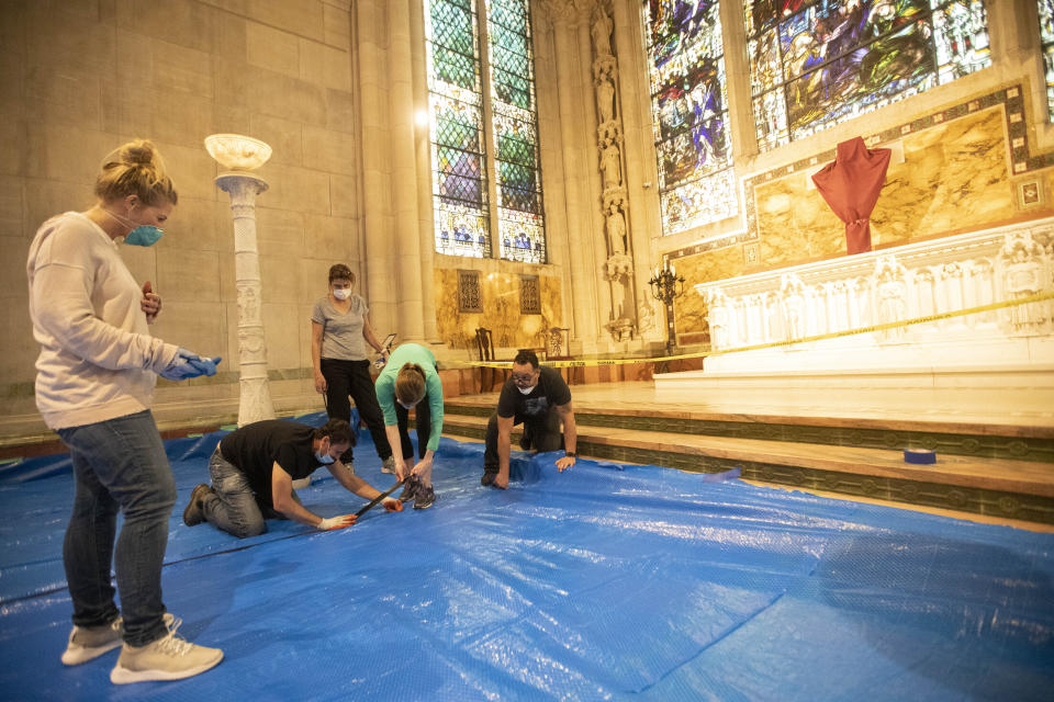 In this April 8, 2020 photo, volunteers tape tarp down on the floor of a chapel while building a field hospital at Cathedral of St. John the Divine in New York. The Cathedral of St. John the Divine had partnered with Mount Sinai Health System and the evangelical Christian organization Samaritan's Purse to provide as many as 200 treatment beds in the church, but the hospital system decided the space was not needed.(AP Photo/Mary Altaffer)