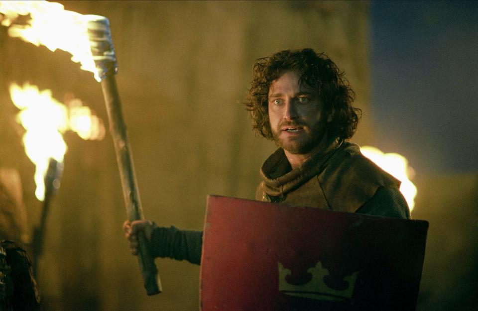 A bearded man holds a torch and a traditional medieval shield