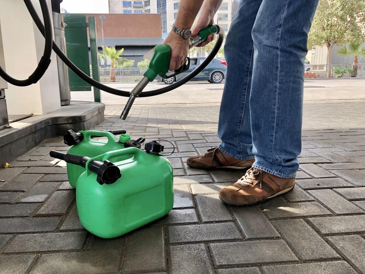 Man filling plastic fuel cans at a petrol station