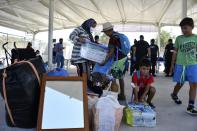 Migrants with their belongings arrive at the new closed monitored facility in Zervou village, on the eastern Aegean island of Samos, Greece, Monday, Sept. 20, 2021. The transfer of the migrants to the new, €43 million ($50 million) facility began Monday and be completed by Wednesday. (AP Photo/Michael Svarnias)