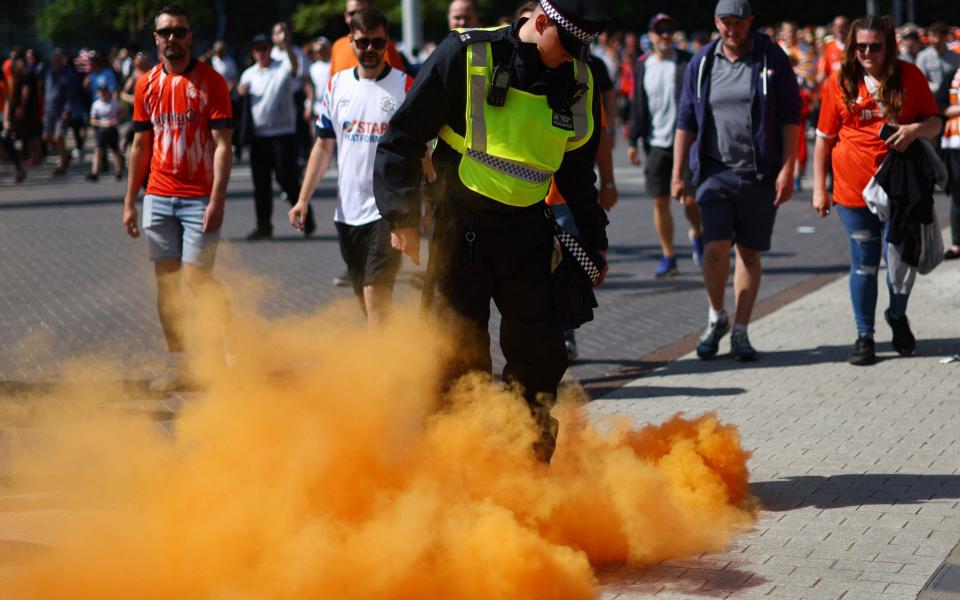 General view of a flare as a police officer is seen outside the stadium - Reuters/Carl Recine