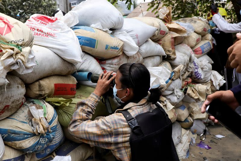 FILE PHOTO: Anti-coup protester looks out through a barricade during a protest against the military rule, in Yangon