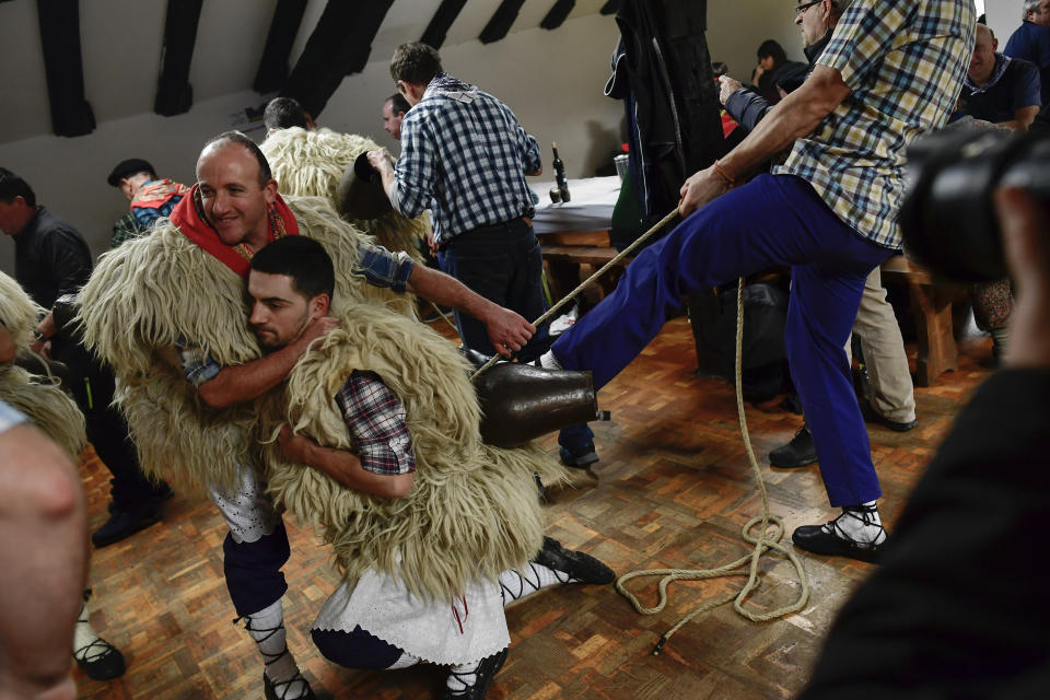 In this Tuesday Jan. 28, 2020 photo, a ''Joaldunak'' is helped to adjust his cowbells before taking part in the Traditional Carnival, in the small Pyrenees village of Ituren, northern Spain. In one of the most ancient carnival celebrations in Europe, dozens of people don sheepskins, lace petticoats and conical caps and sling cowbells across their lower backs as they parade to herald the advent of spring. (AP Photo/Alvaro Barrientos)