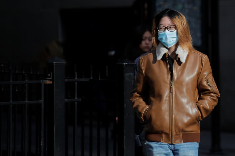 A woman wears a mask on Wall St. near the NYSE in New York