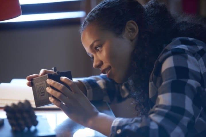 A girl tries to solve a puzzle box.