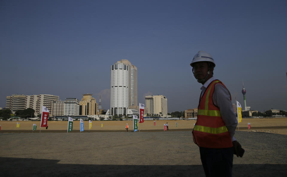 FILE - In this Jan. 2, 2018, file photo, a Chinese construction worker stands on land that was reclaimed from the Indian Ocean for the Colombo Port City project, initiated as part of China's ambitious One Belt One Road initiative, in Colombo, Sri Lanka. India has tried to counter China's billion-dollar investments and high-interest loans to Sri Lanka, Bangladesh, the Maldives, Bhutan and Nepal, which Indian officials have referred to as debt traps, by upping its foreign aid to those countries. Chinese President Xi Jinping is coming to India to meet with Prime Minister Narendra Modi on Friday, Oct. 11, 2019, just weeks after Beijing supported India's rival Pakistan in raising the issue of New Delhi's recent actions in disputed Kashmir at the U.N. General Assembly meeting. (AP Photo/Eranga Jayawardena, File)