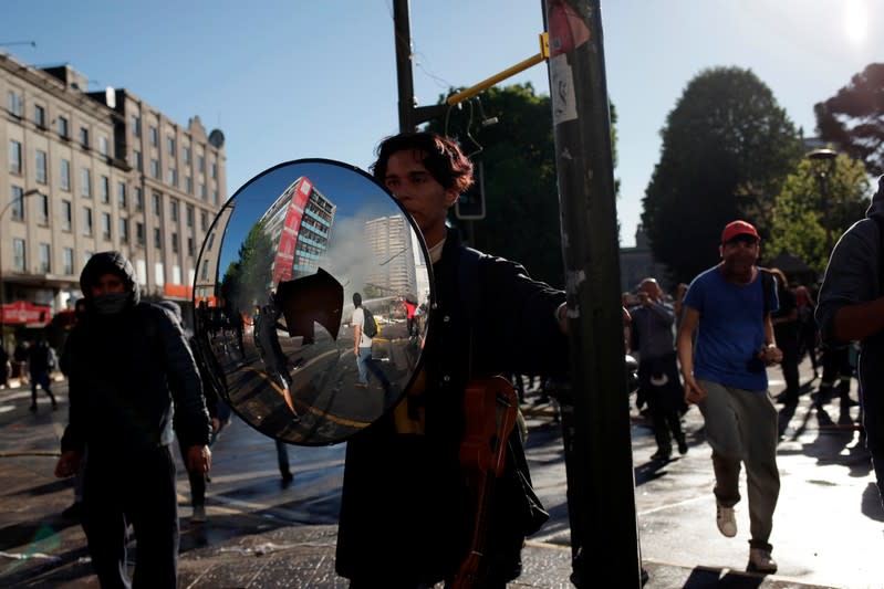 Un manifestante usa un espejo de tránsito para protegerse durante las protestas en Chile.