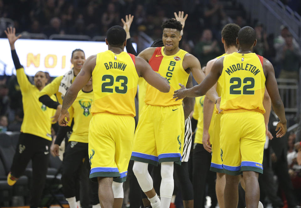 Milwaukee Bucks’ Giannis Antetokounmpo, middle, gives high-fives to Sterling Brown (23) and Khris Middleton (22) during the first half of an NBA basketball game Sunday, April 7, 2019, in Milwaukee. (AP Photo/Aaron Gash)