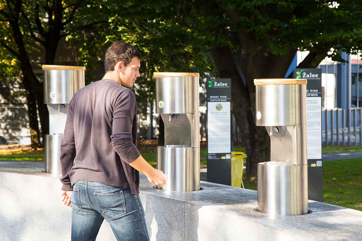 Žalec, Slovenia - October 01, 2016: A young man pours beer into a glass at public beer fountain in Žalec, Slovenia, the first beer fountain in the World