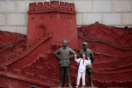 A girl takes a selfie with statues depicting late Chinese chairman Mao Zedong (L) and former general Zhu De during the War of Resistance against Japan, at Jianchuan Museum Cluster in Anren, Sichuan Province, China, May 13, 2016. REUTERS/Kim Kyung-Hoon