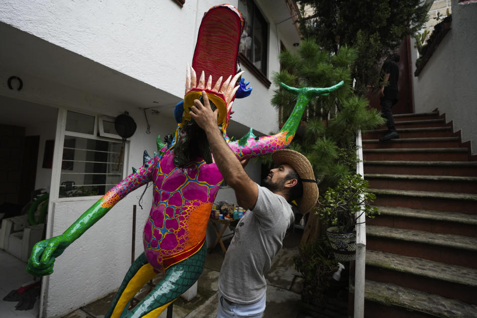 El artista mexicano Israel Mondragón coloca la cabeza de su alebrije en su taller para el desfile anual en Ciudad de México, el jueves 19 de octubre de 2023. Los alebrijes representan criaturas fantásticas y están hechos de cartón pintado con llamativos colores. (AP Foto/Fernando Llano)