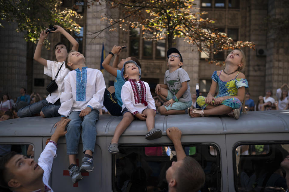 FILE - In this Friday, Aug. 24, 2018 file photo children look up as military aircrafts fly above the city center during a military parade to celebrate Independence Day in Kiev, Ukraine. (AP Photo/Felipe Dana, File)