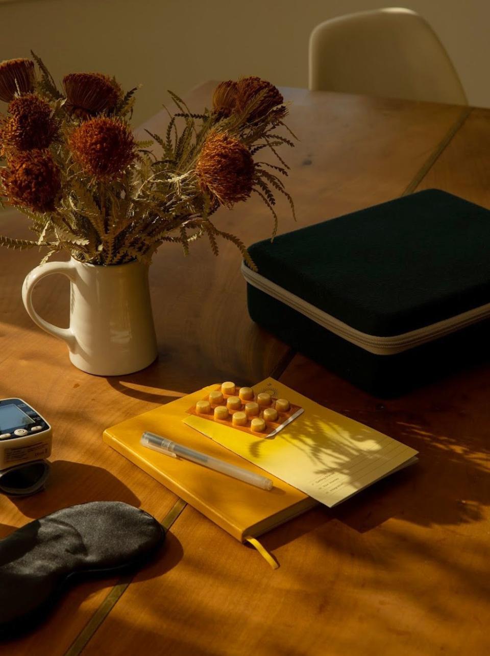 a table with a vase of flowers and a book