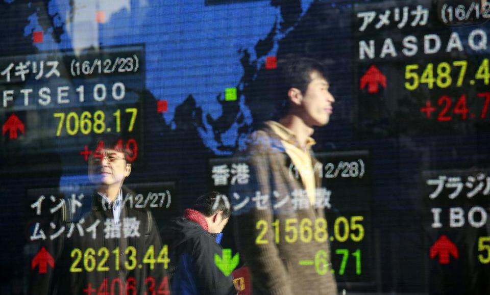 People are reflected on an electronic stock indicator of a securities firm in Tokyo, Wednesday, Dec. 28, 2016. Shares meandered in quiet trading in Asia on Wednesday after the Dow Jones industrial average inched closer to 20,000 and the Nasdaq Composite rose to a record high. (AP Photo/Shizuo Kambayashi)