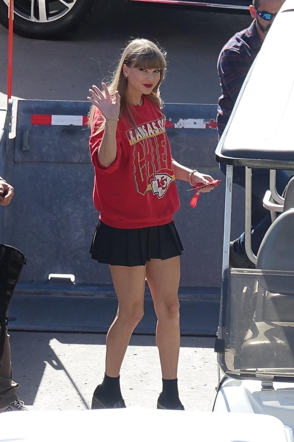 Taylor is wearing a Chief's sweatshirt with a short pleated skirt