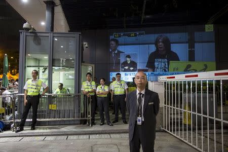 A live broadcast showing League of Social Democrats legislator "Long Hair" Leung Kwok-hung is seen behind security officers of Legislative Council during a demonstration in Hong Kong, China June 17, 2015. REUTERS/Tyrone Siu