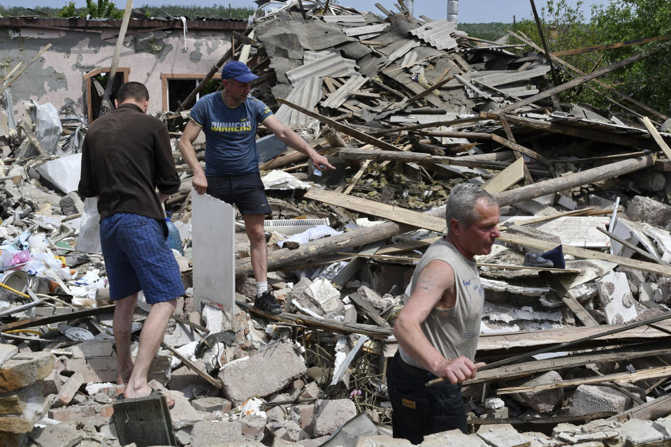 People clean an area of a building damaged by an overnight missile strike in Sloviansk, Ukraine, Wednesday, June 1, 2022. (AP Photo/Andriy Andriyenko)