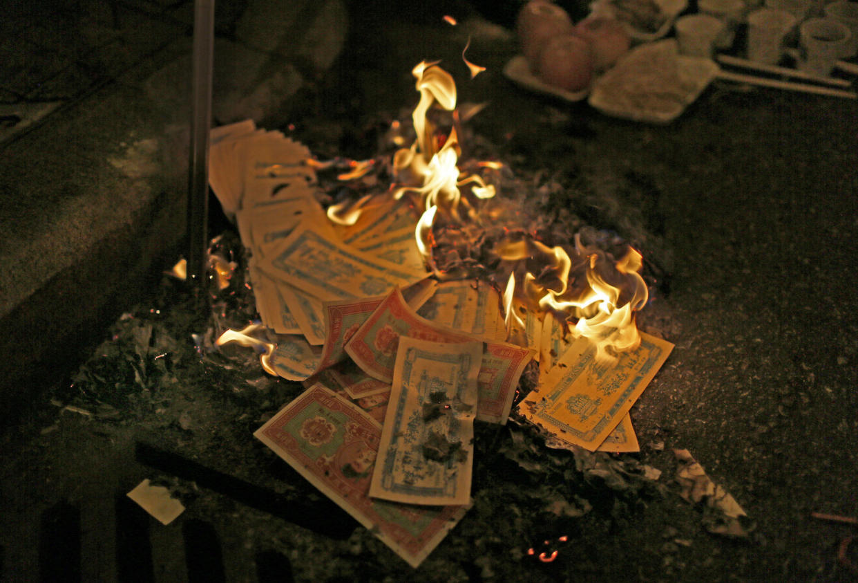 Stock image of burnt paper money. (AP Photo/Vincent Yu)