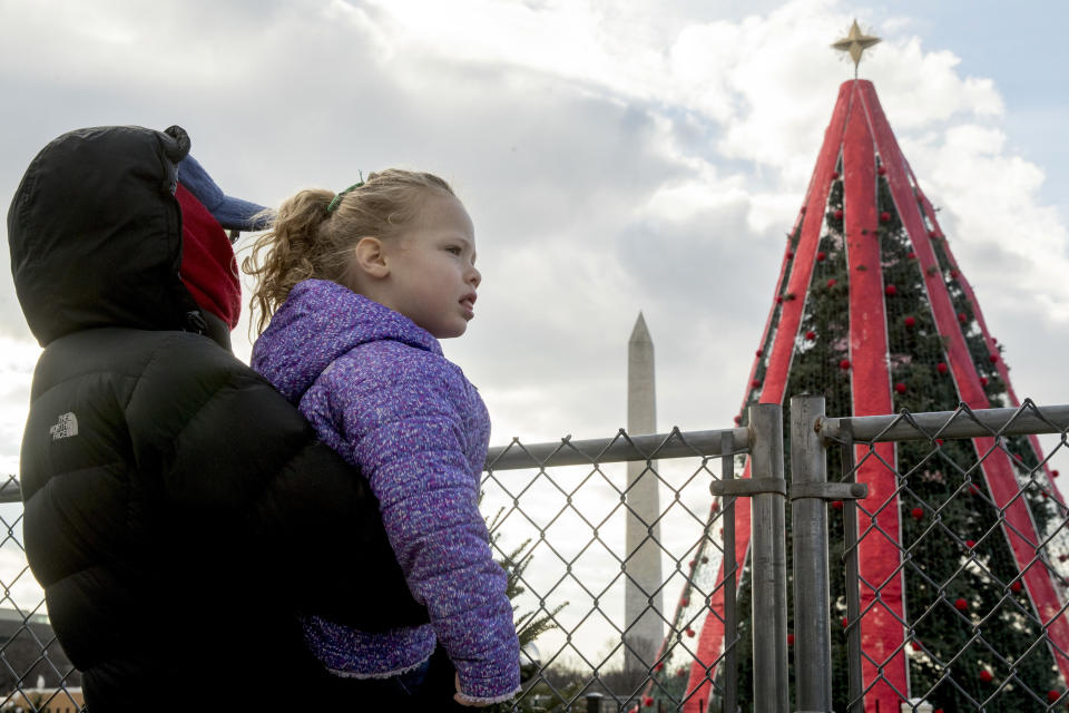 Susie Schultz, of St. Louis, holds her granddaughter up over a fence to look at the National Christmas Tree on the Ellipse near the White House, Dec. 24, 2018. (Photo: Andrew Harnik/AP)