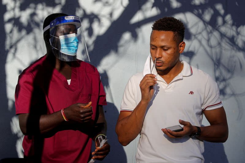 A healthcare worker stands by as a man takes a test for the coronavirus disease (COVID-19) in Staten Island, New York