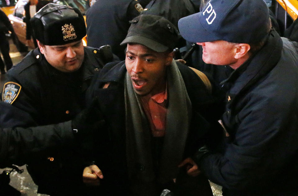 Police arrest a protestor rallying against a grand jury's decision not to indict the police officer involved in the death of Eric Garner near Times Square, Thursday, Dec. 4, 2014, in New York. A grand jury cleared a white New York City police officer Wednesday in the videotaped chokehold death of Garner, an unarmed black man, who had been stopped on suspicion of selling loose, untaxed cigarettes. (AP Photo/Jason DeCrow)