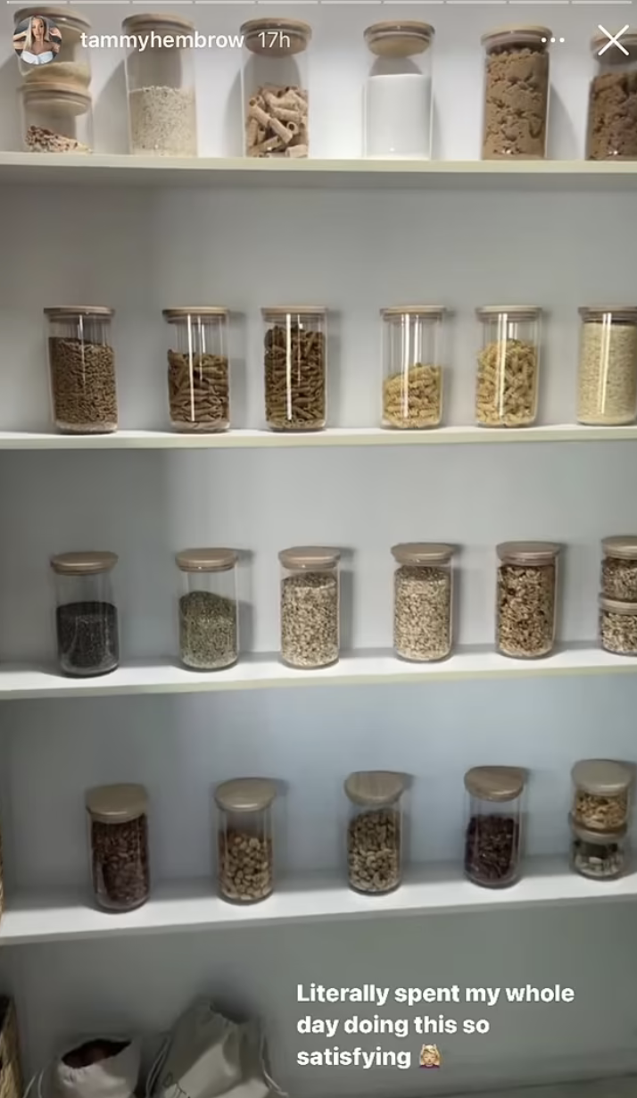 Inside Tammy Hembrow's pantry showing pasta, rolled oats etc in round glass jars with wooden lids