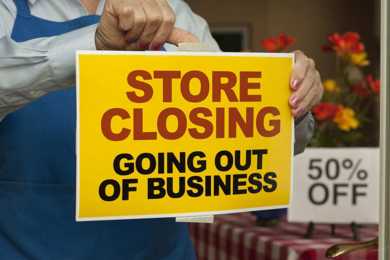 employee putting up store closing sign in window