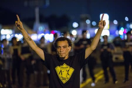 Anti-police demonstrators gesture at a line of St Louis County police officers during protests in Ferguson, Missouri August 11, 2015. REUTERS/Lucas Jackson