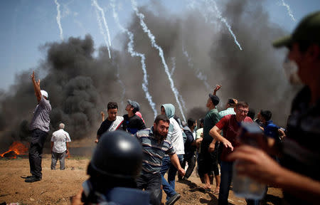 Palestinian demonstrators run for cover from tear gas fired by Israeli troops during a protest marking al-Quds Day, (Jerusalem Day), at the Israel-Gaza border, east of Gaza City June 8, 2018. REUTERS/Mohammed Salem