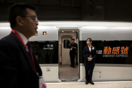 An attendant stands next to an entrance of a Guangzhou-Shenzhen-Hong Kong Express Rail Link (XRL) Vibrant Express train bound for Guangzhou Nan Station on a platform in the Mainland Port Area at West Kowloon Station, which houses the terminal for the XRL, developed by MTR Corp., in Hong Kong, China, September 22, 2018. Giulia Marchi/Pool via REUTERS