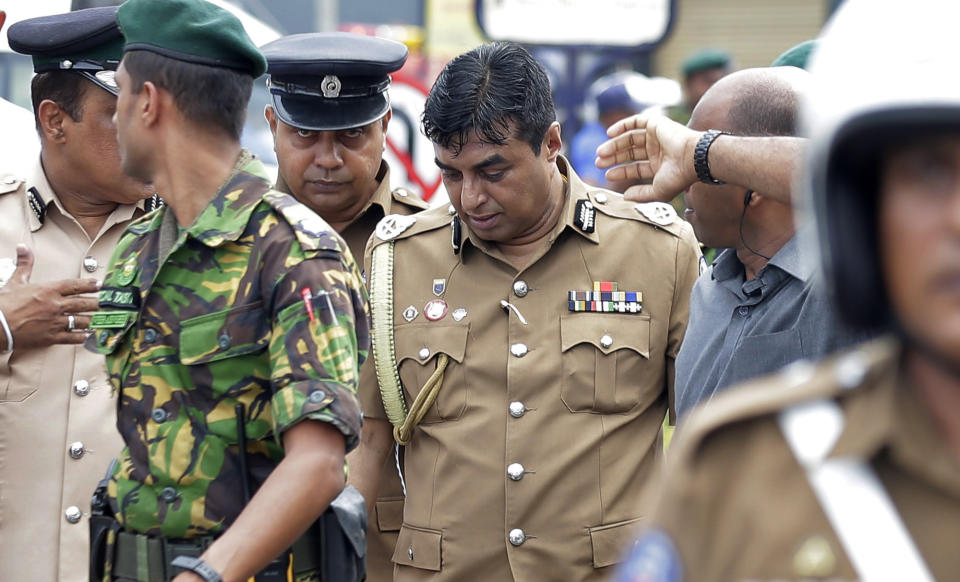 In this April 21, 2019 photo, Sri Lankan police chief Pujith Jayasundara, center, leaves after an inspection at St. Anthony's church, one of the sites of Easter Sunday explosions in Colombo, Sri Lanka. Sri Lankan police on Tuesday arrested the country's police chief, currently on compulsory leave, and its former defense secretary for alleged negligence leading to the Easter Sunday bombings that killed more than 250 people at churches and hotels. (AP Photo/Eranga Jayawardena)