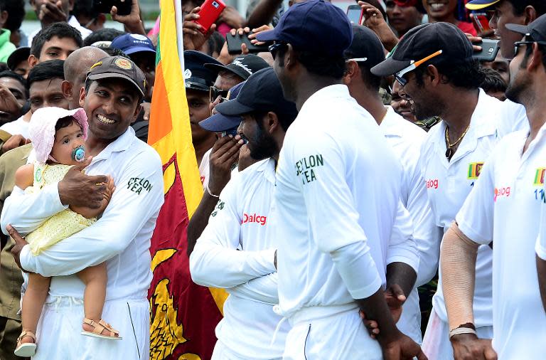 Sri Lanka's cricketer Mahela Jayawardene (L) holds his daughter Sansana as his teammates and wife look on at the Sinhalese Sports Club (SSC) Ground in Colombo on August 18, 2014