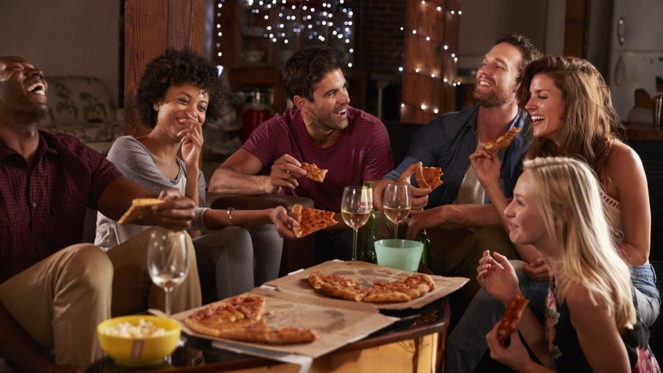 young adults sharing pizzas at a party at home
