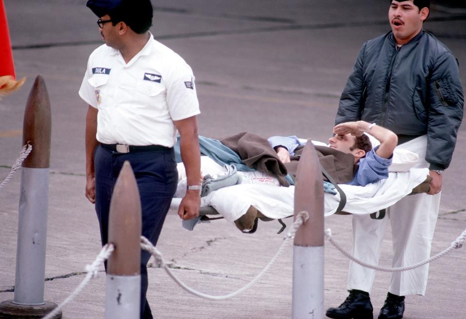 Former POW and U.S. Air Force TSGT James R. Cook salutes the colors from his stretcher as he is carried from the C-141 aircraft.  TSGT Cook was captured on 21 Dec 72 and released by the North Vietnamese in Hanoi 12 Feb 73. U.S. Air Force photo.