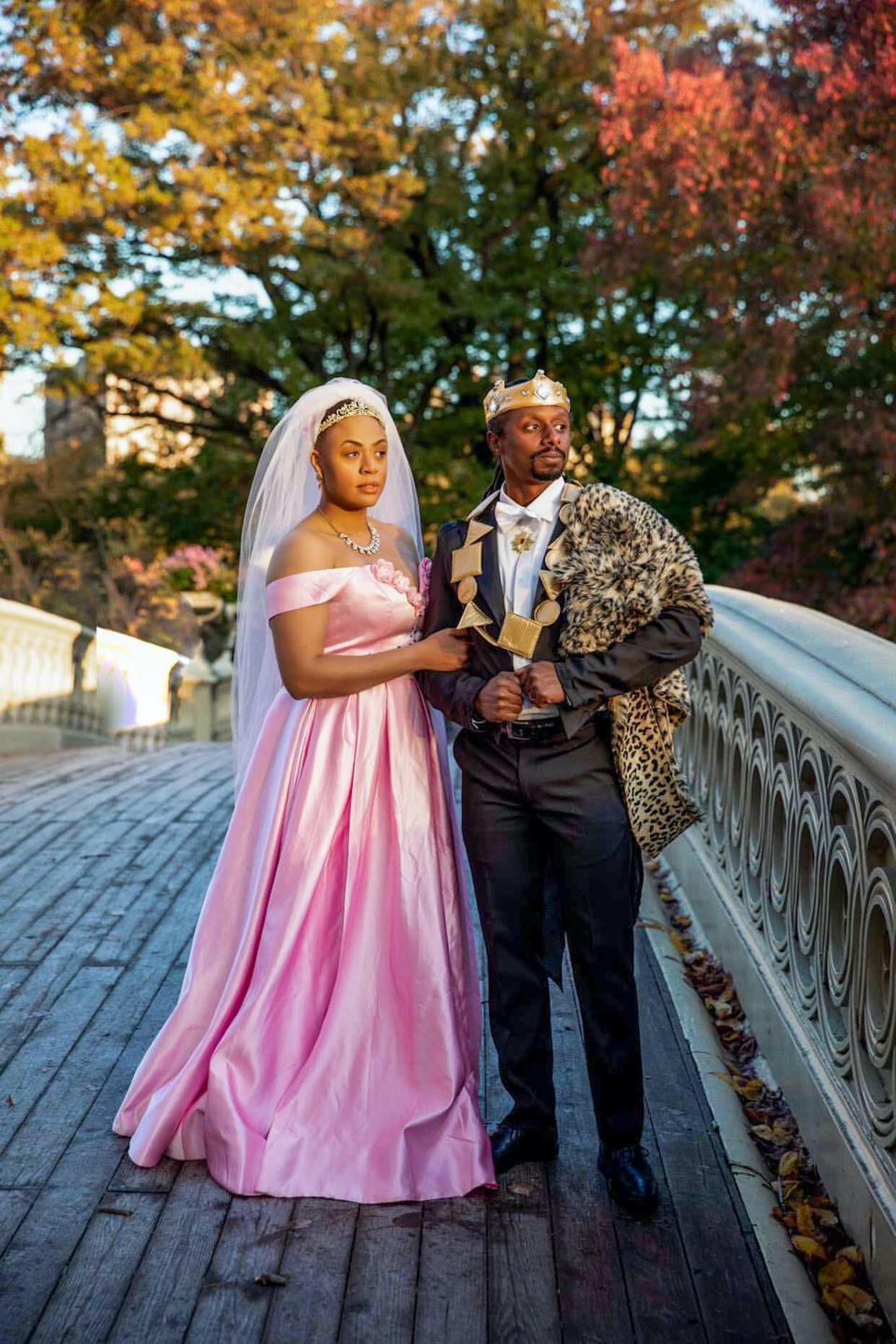 A couple dressed as Lisa and Prince Akeem pose for a photo on a bridge.