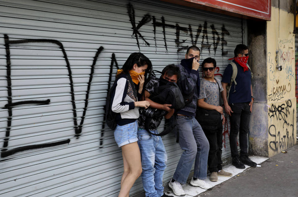 Anti-government demonstrators take cover under a ledge during clashes with police in Santiago, Chile, Wednesday, Oct. 23, 2019. Tens of thousands of protesters have taken to the streets Chile's capital as an apology and promises of reform from President Sebastián Piñera failed to quell turmoil that has led to looting, rioting and at least 18 deaths. (AP Photo/Rodrigo Abd)