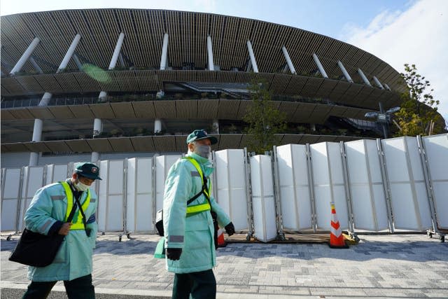 Parking inspectors wearing face masks to protect against the spread of the coronavirus walk past the Japan National Stadium, where opening ceremony and many other events are planned for postponed Tokyo 2020 Olympics 